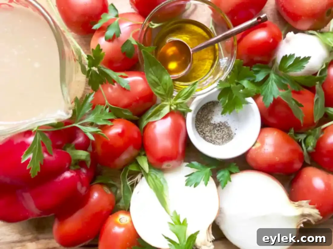 Fresh plum tomatoes, onion, and red bell pepper on a baking sheet before roasting for creamy roasted tomato soup