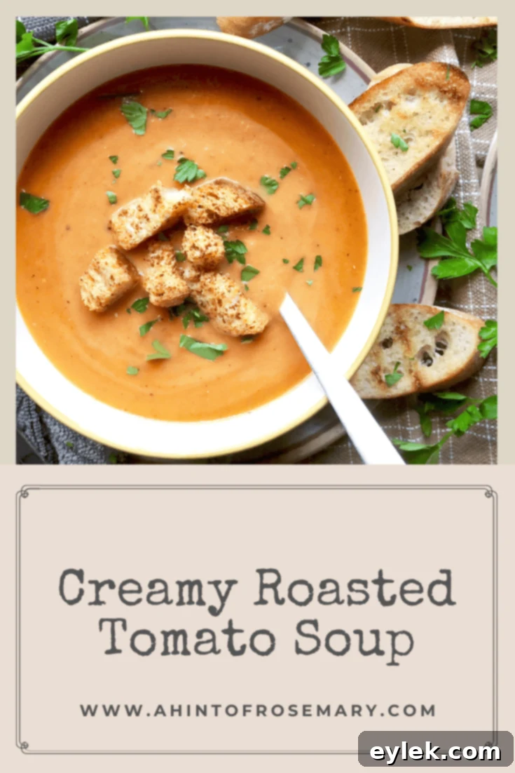 Two bowls of creamy roasted tomato soup, one garnished with fresh herbs and a swirl of cream, on a wooden surface.