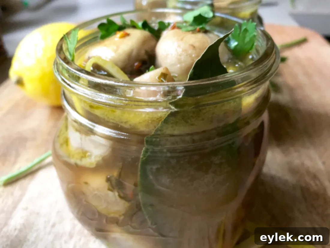 Small glass jars filled with marinated mushrooms, garnished with fresh parsley and lemon peel.