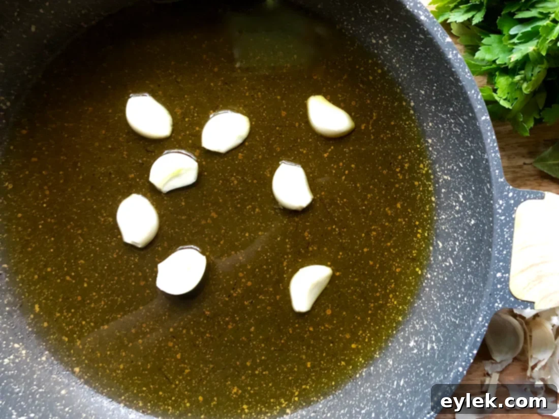 Halved garlic cloves sautéing in olive oil in a skillet.