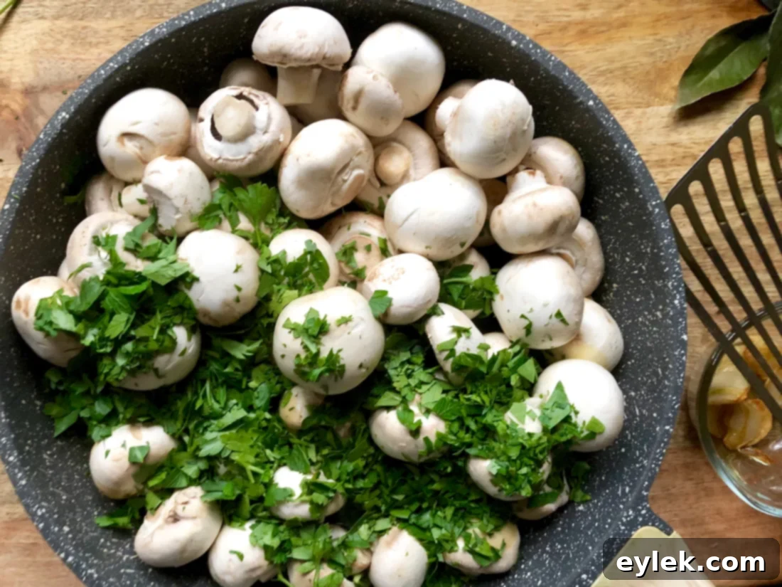 Mushrooms and parsley sautéing in a skillet, turning golden brown.