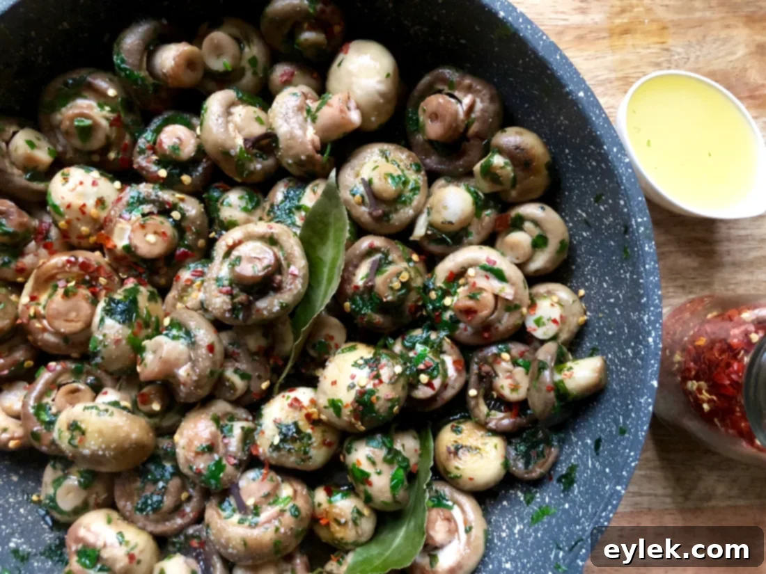 Mushrooms simmering in a rich marinade within a skillet.