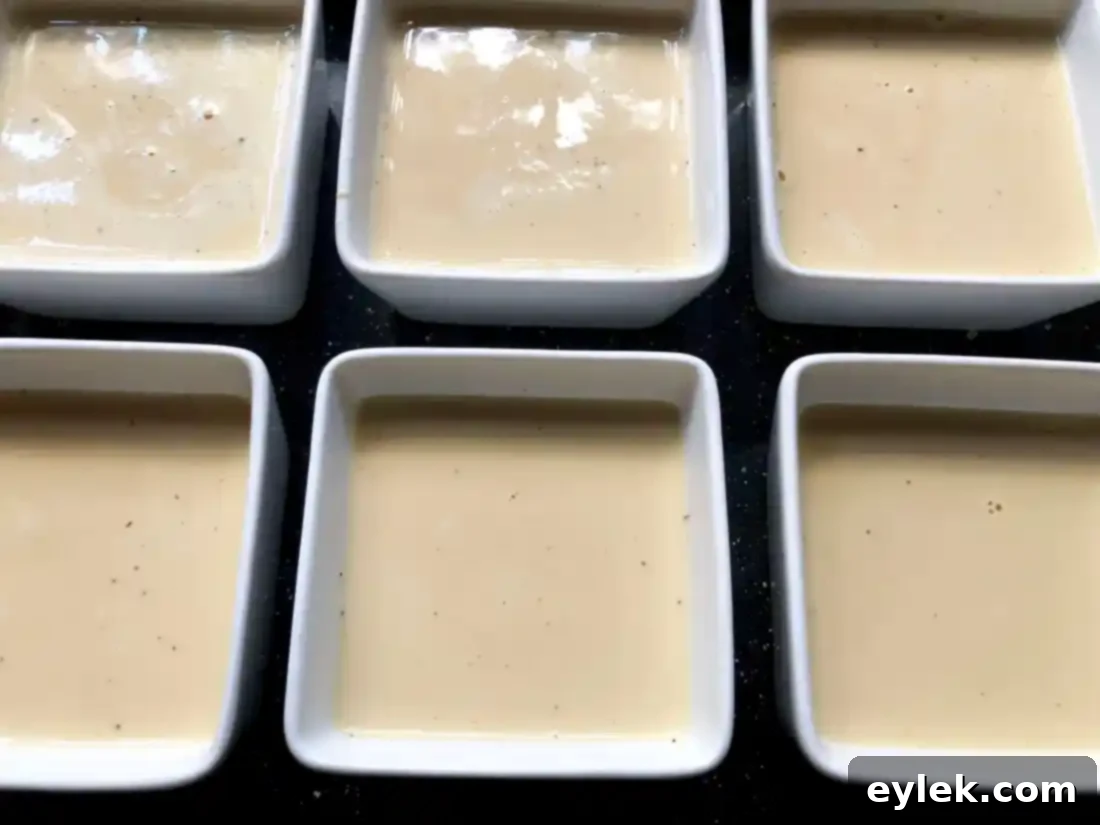 Custard filled ramekins in a water bath, covered with foil