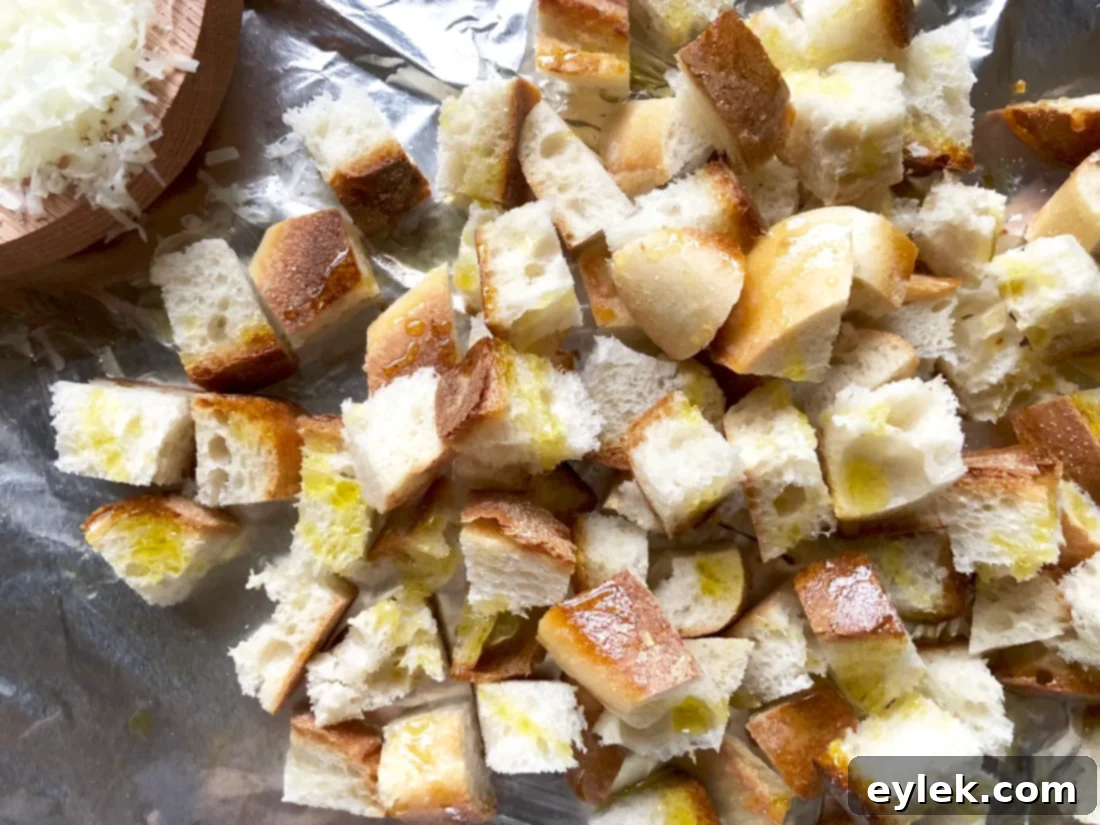 Manchego cheese sprinkled over bread cubes on a baking sheet