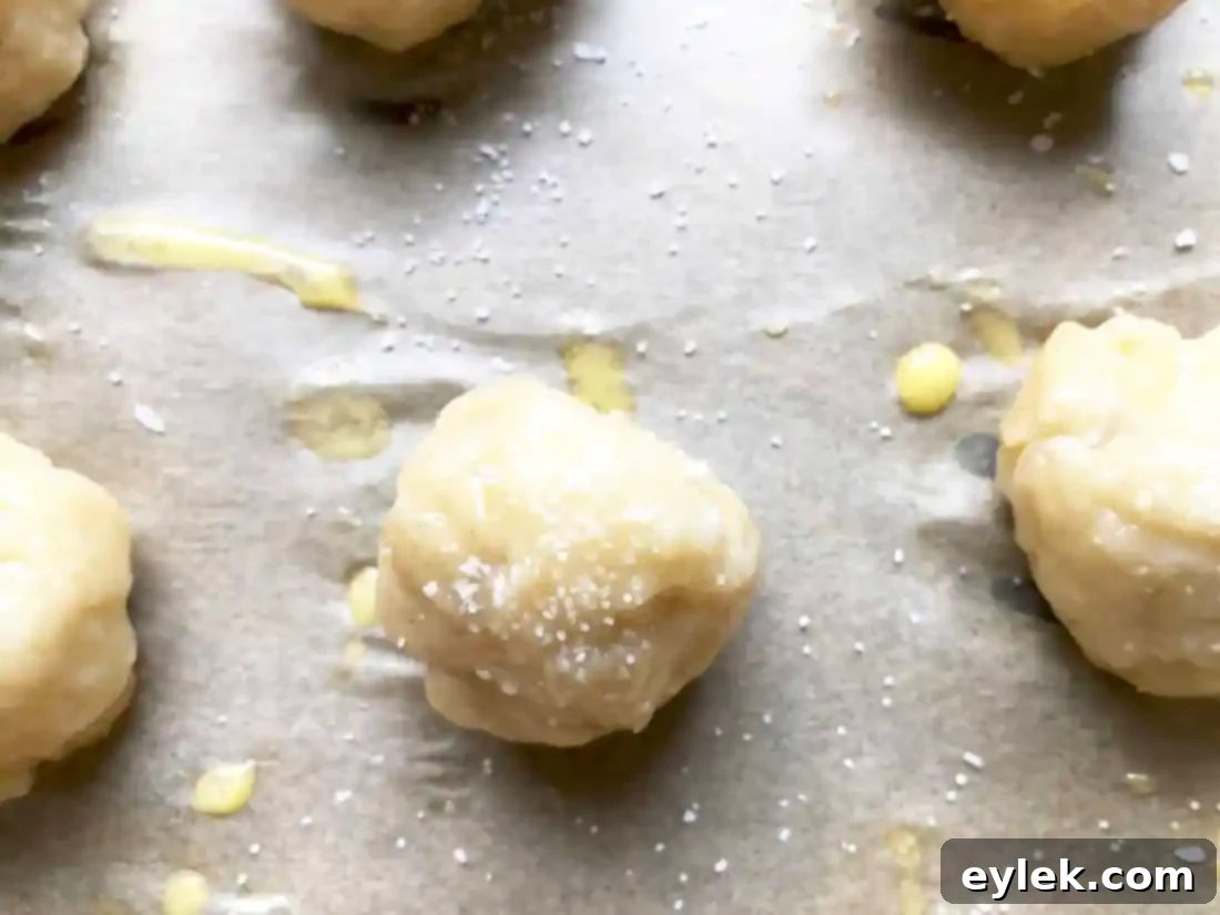 Pretzel dough balls arranged on a parchment-lined baking sheet