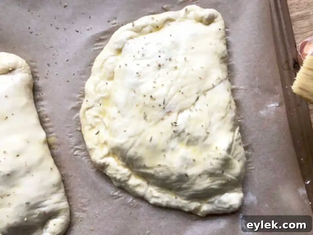 Two fully assembled and sealed chicken and mushroom calzones, ready for baking