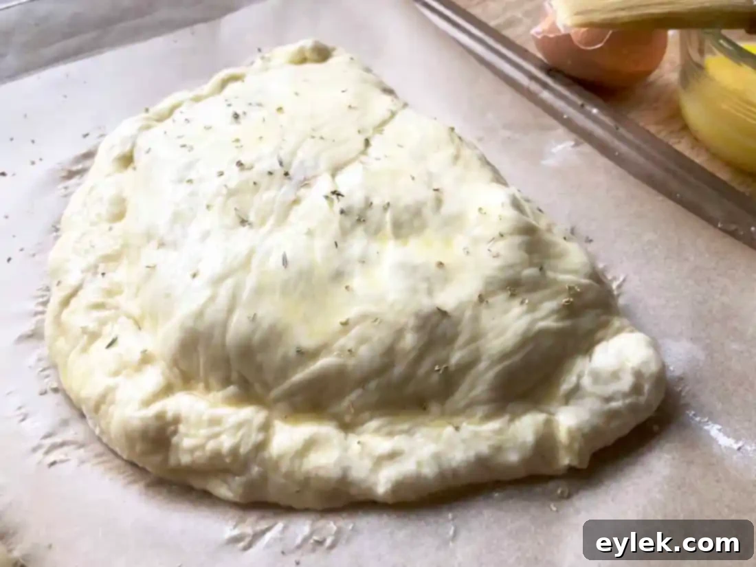 Calzones brushed with egg wash and sprinkled with Italian seasoning, ready for the oven