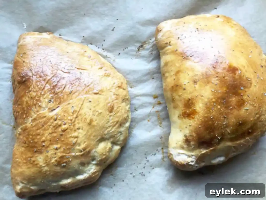 Freshly baked golden-brown chicken and mushroom calzones cooling on a wire rack