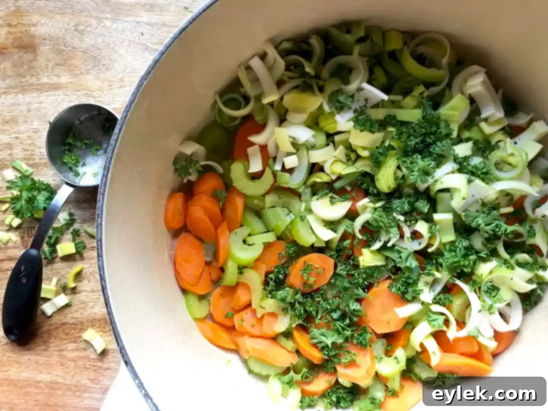 Carrots, celery, and leeks sautéing in a pot with a lid on.