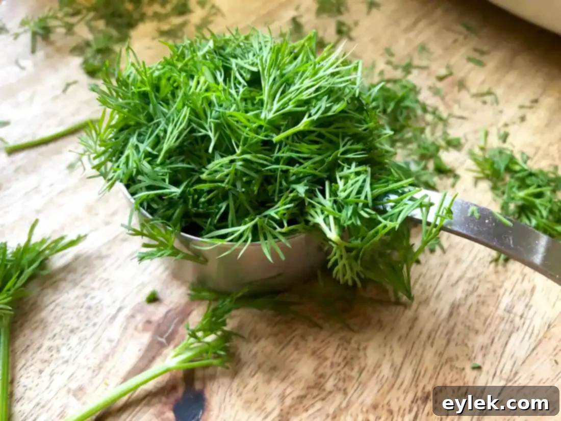 Chicken broth and fresh dill added to sautéed vegetables in a pot.