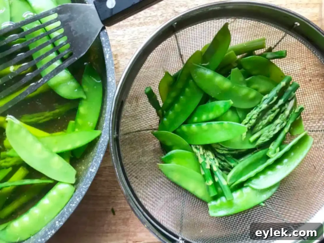 Blanched snow peas and asparagus cooling under cold water