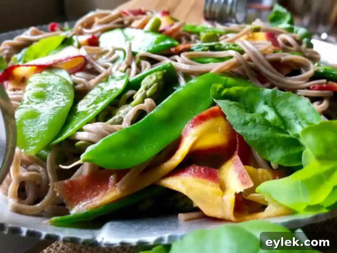 A serving of Soba, Snow Pea & Asparagus Toss garnished with fresh basil in a bowl