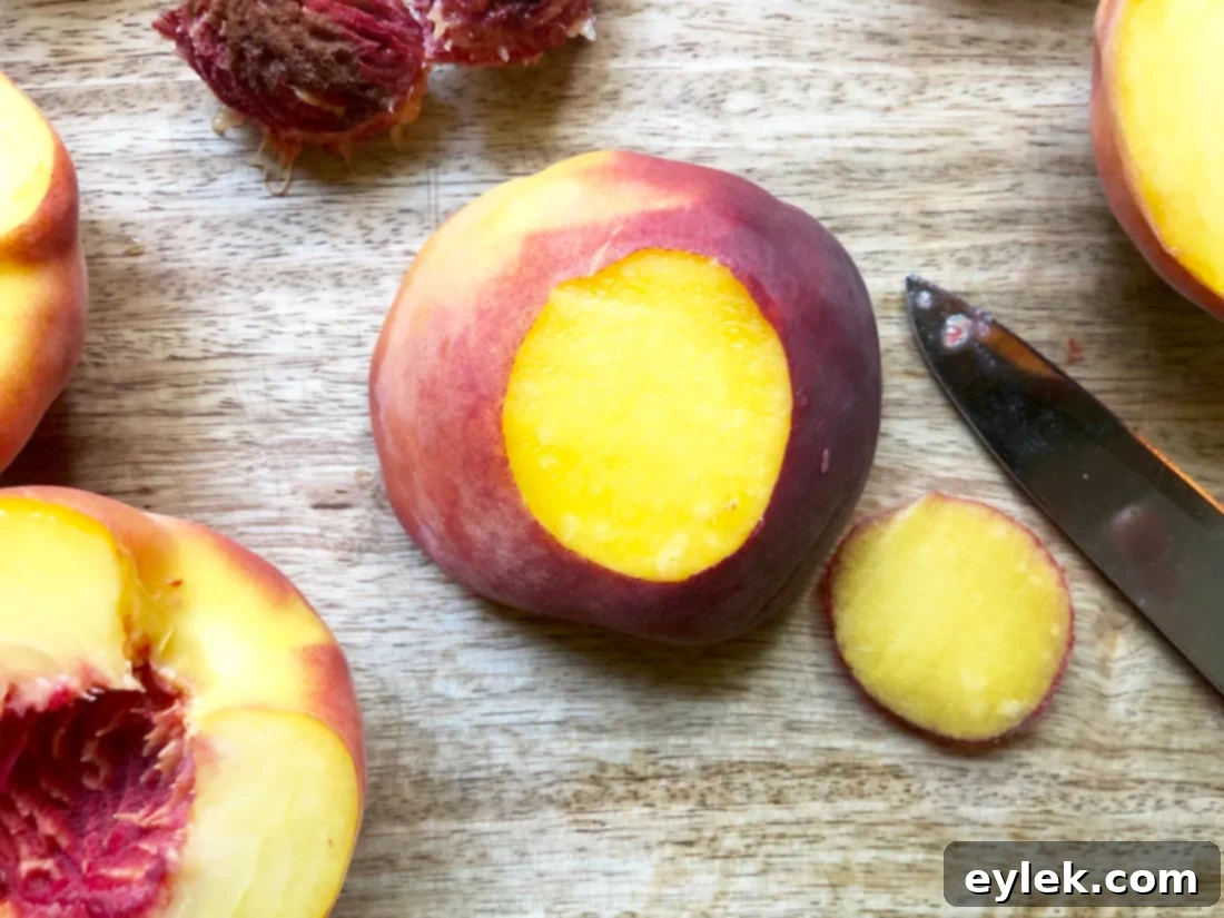 Peach halves arranged on a baking sheet, coated with cinnamon sugar