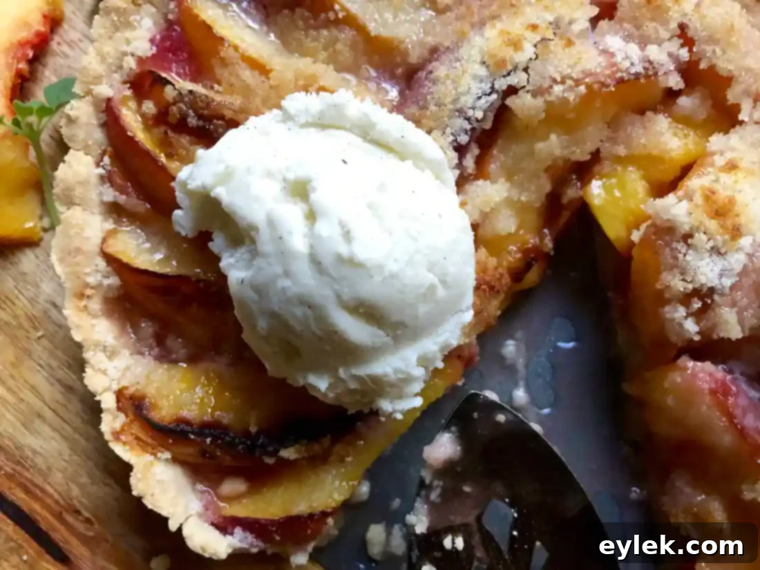 Beautiful peach tart with a slice removed, showing golden crust and fruit filling