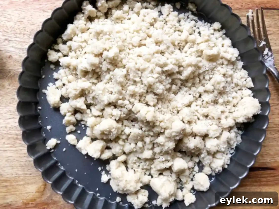 Preparing the crust by pressing dough into a tart pan