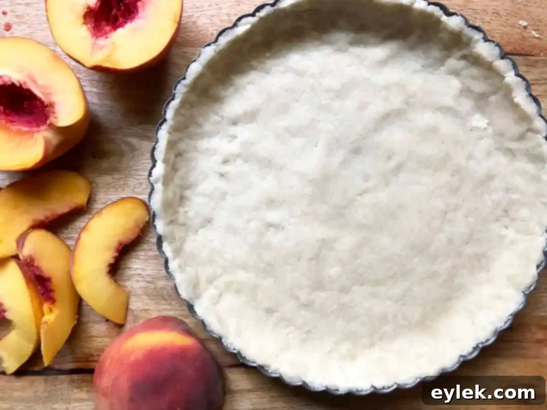 Arranging fresh peach slices in a concentric pattern on the tart crust