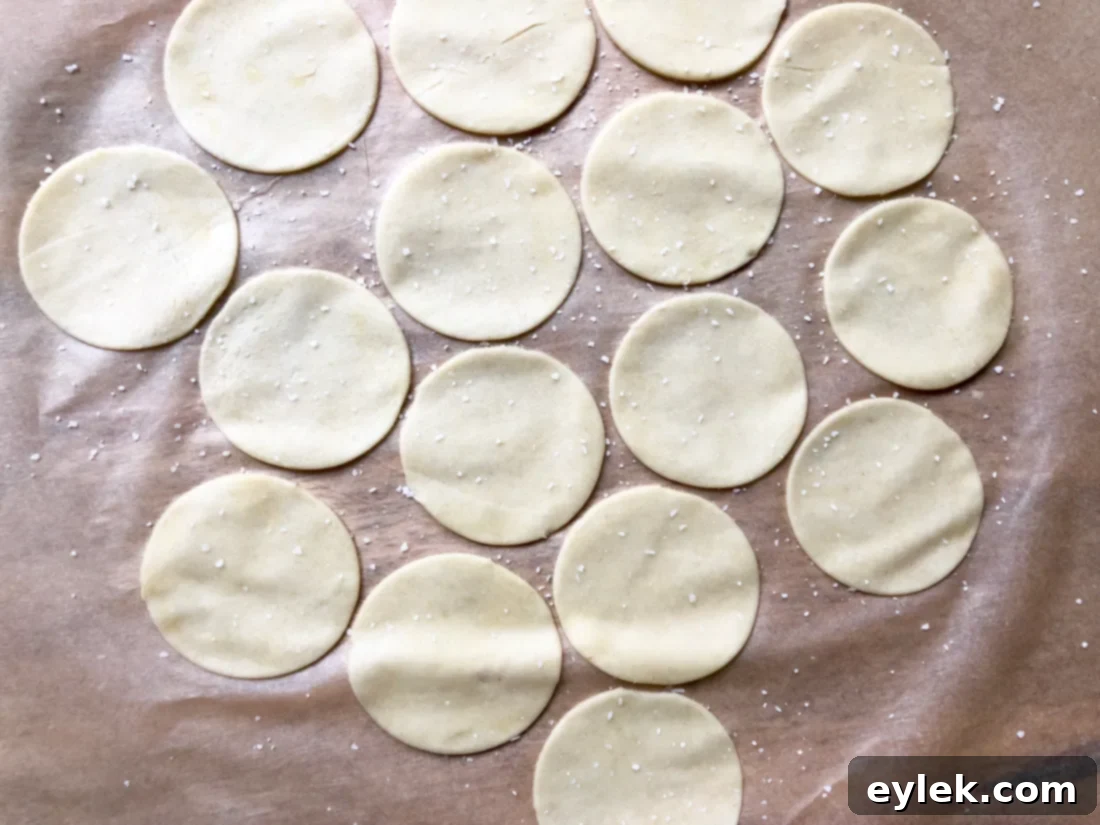 Seasoned einkorn cheese cracker cutouts on parchment paper, ready to bake