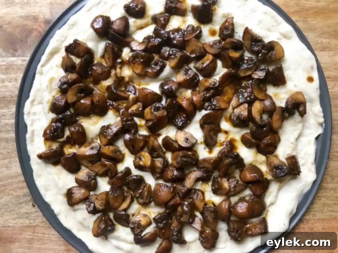Unbaked Mushroom Marsala Pizza, fully assembled with toppings and cheese.