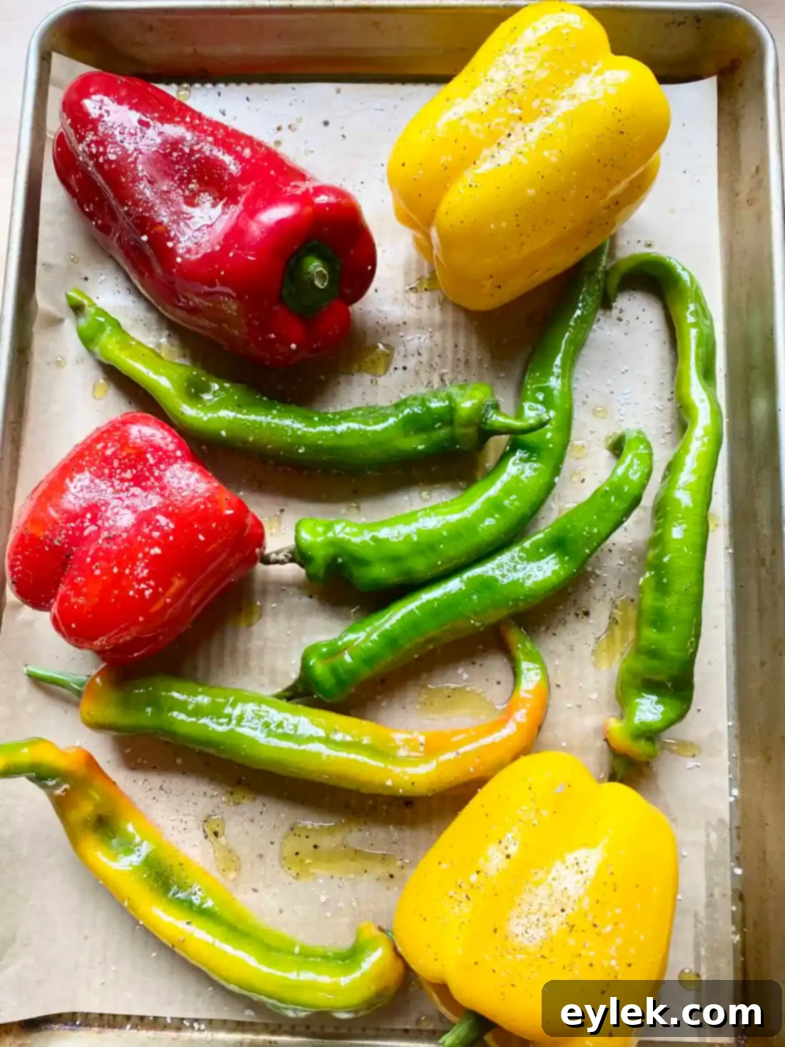 Peppers coated in olive oil on a baking sheet