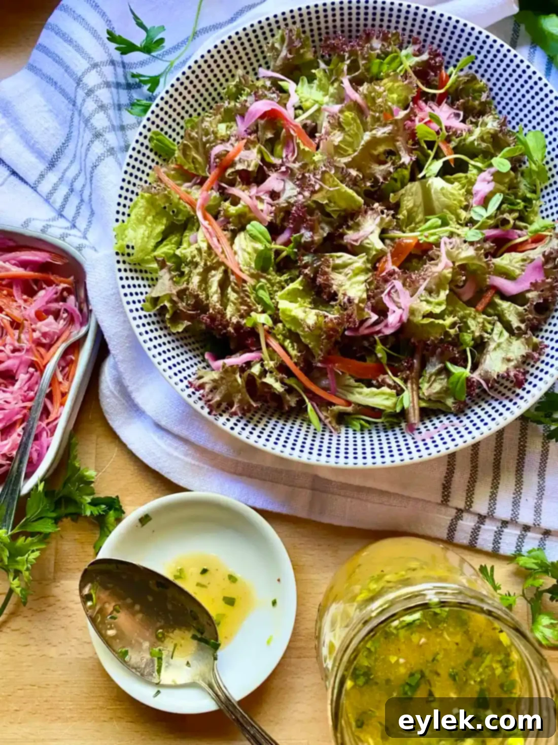 A fresh green salad being drizzled with the homemade French Dijon Vinaigrette.